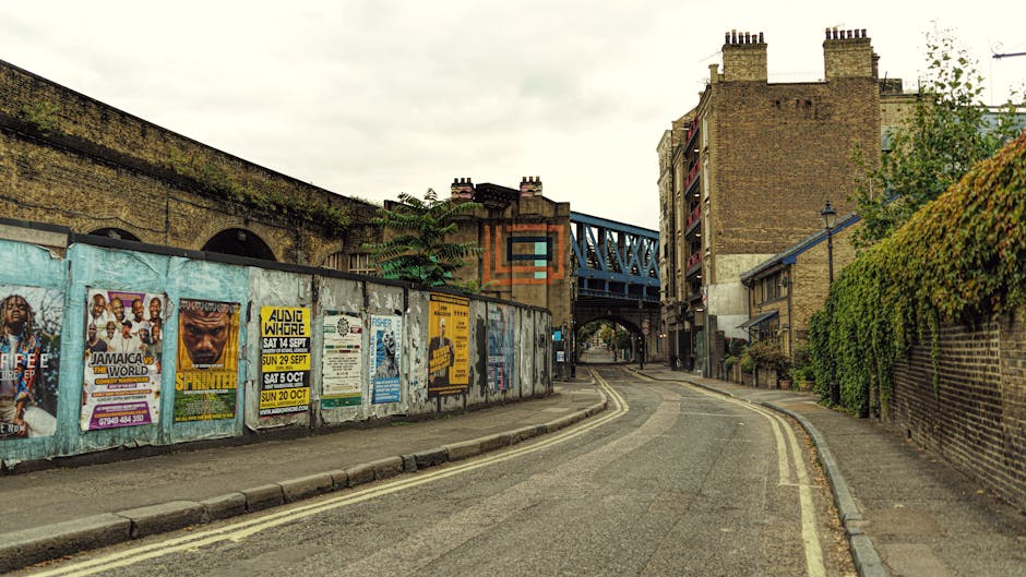 A street scene in Denmark Hill showing a slight curve in the road with parked cars lining both sides, including a silver Audi in the foreground and multiple vehicles further down, such as a red double